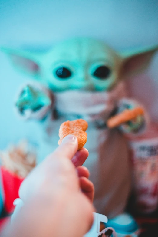 a person holding food with the baby yoda in the background