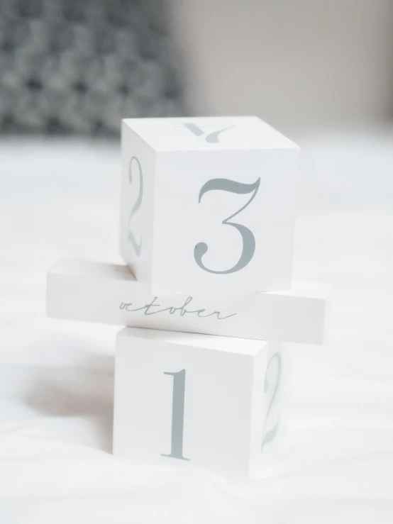 three blocks with a number are stacked high on the bed