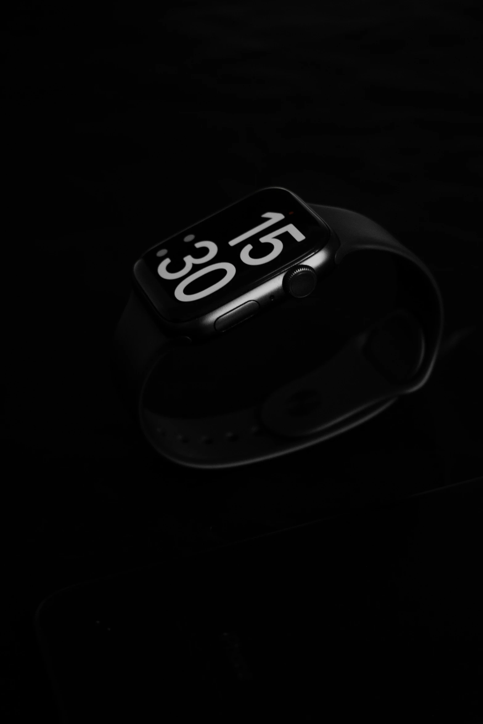 an apple watch on a black surface with the time displayed