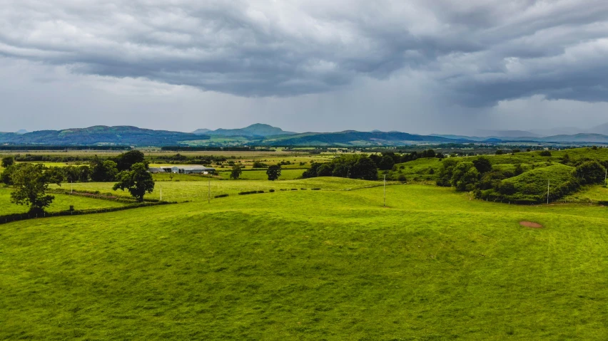 a big green field in the middle of mountains