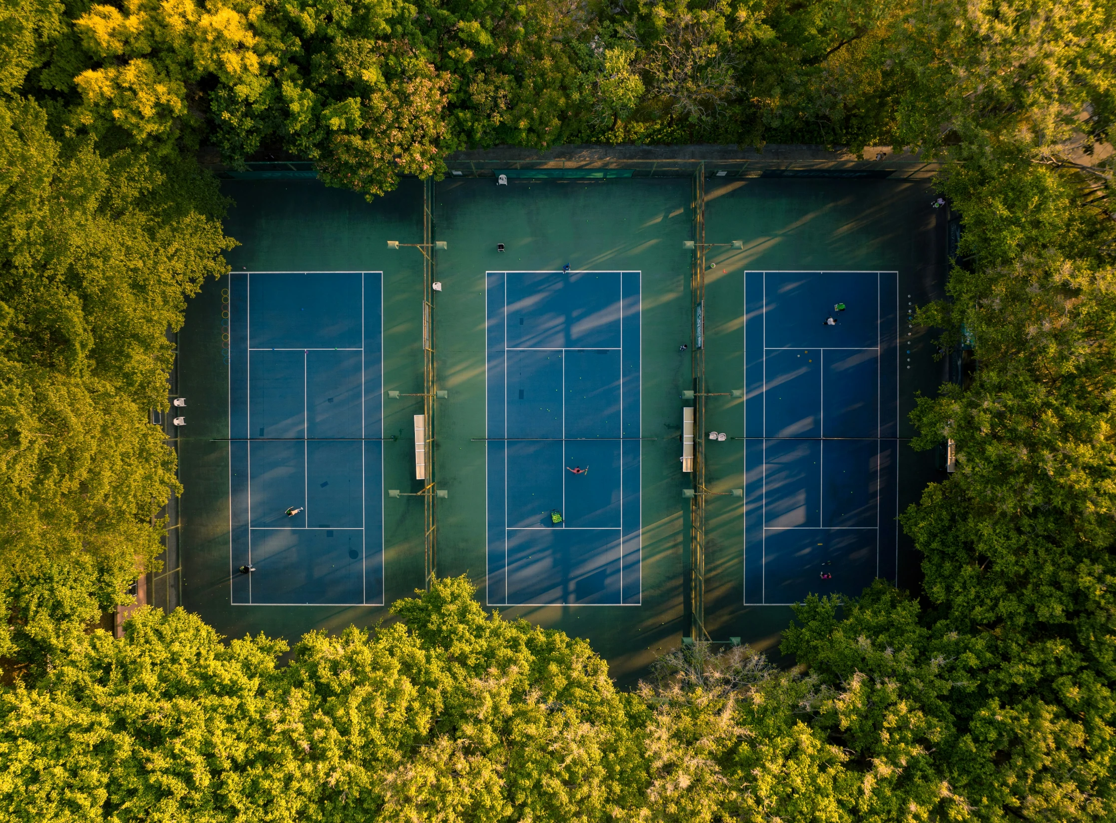 an aerial view of two tennis courts surrounded by trees