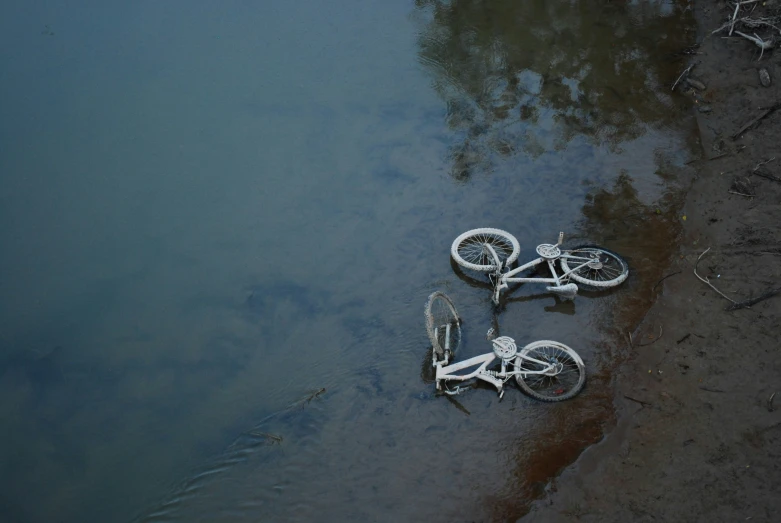 two bikes parked in the water beside each other