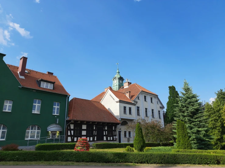 a green house with red tiled roof and trees