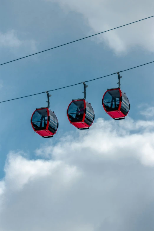 three people are riding a ski lift on the sky