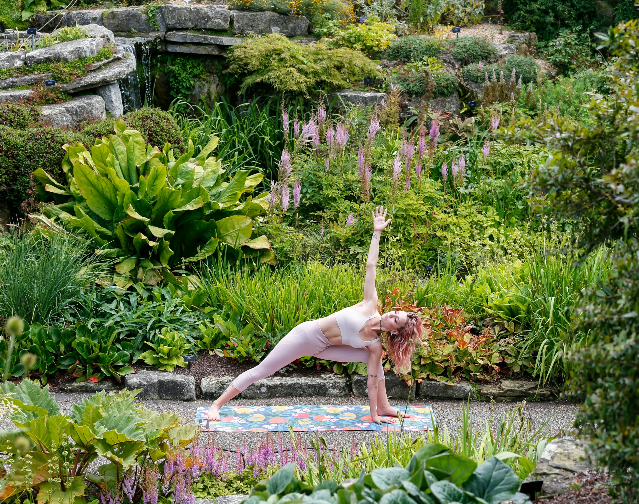 a  woman stretching in the middle of a lush garden