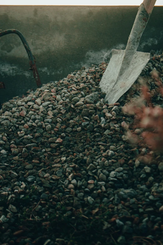 a bunch of small rocks sitting next to a large shovel