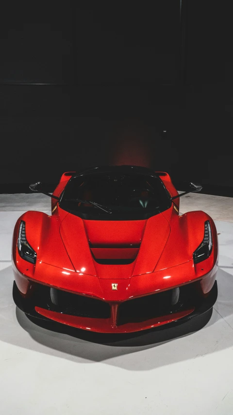 a red sports car sits in the middle of a dark room