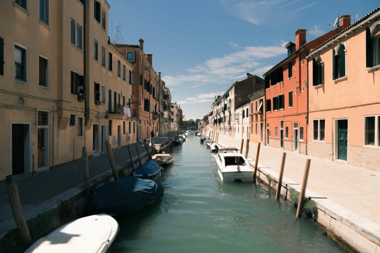 small boats floating along the side of a river next to tall buildings