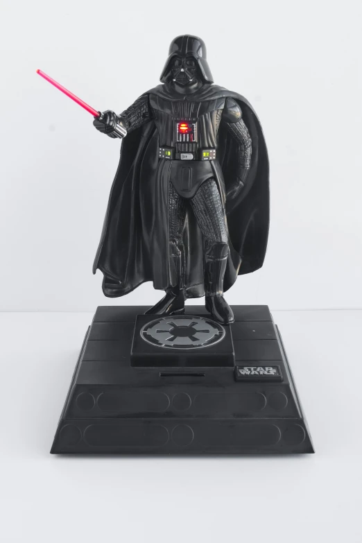 a toy darth vader on a black stand with a red light shining down it
