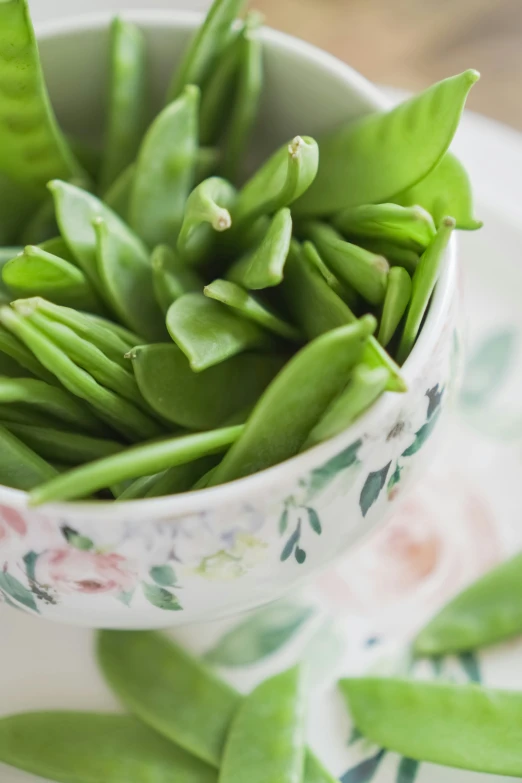 a bowl with snap peas in it on a plate