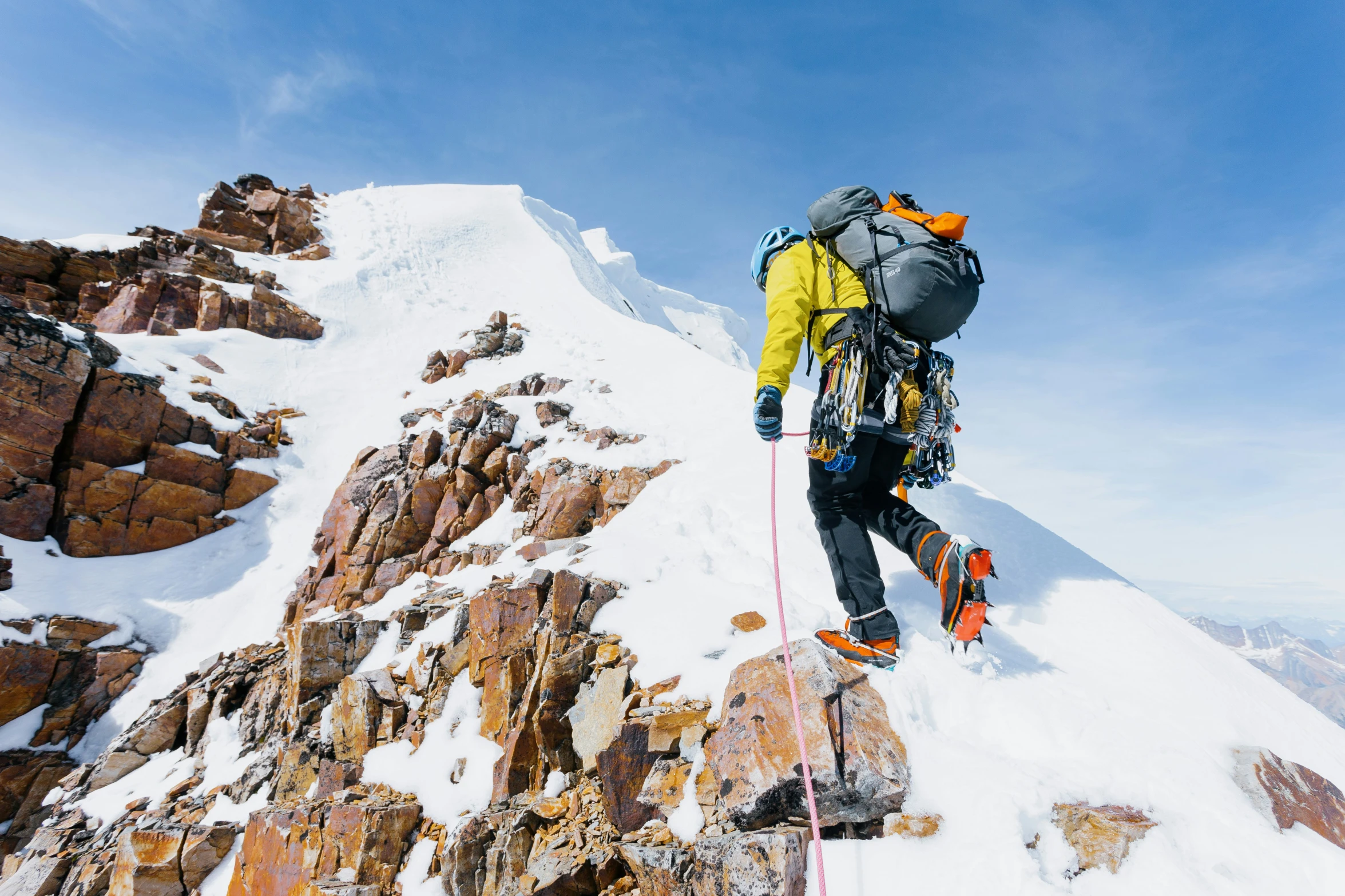 a climber walking on the snow next to the rocky mountain