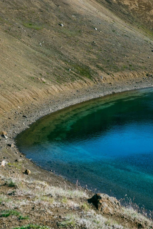 the man is laying on the top of a hill by the water