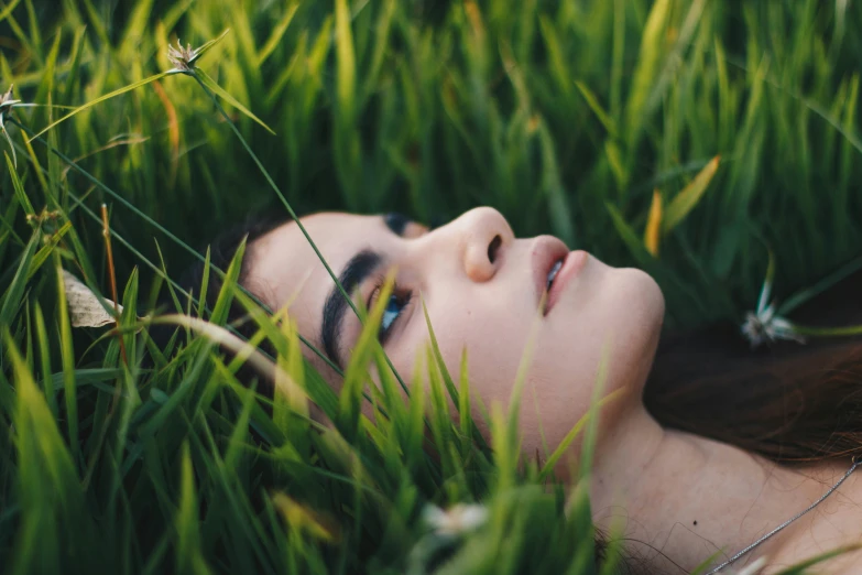 a young woman in the middle of tall grass looking into the sky