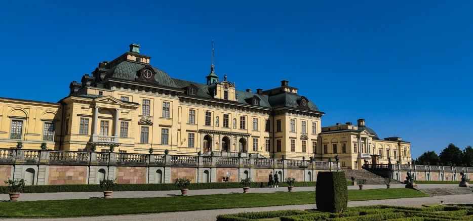 the large yellow building is by itself in a garden