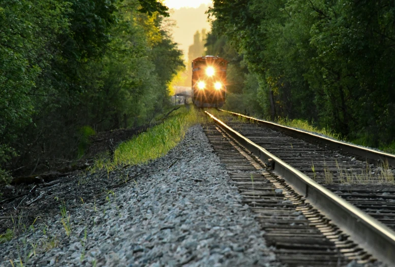 a train engine with lights on is traveling down the track