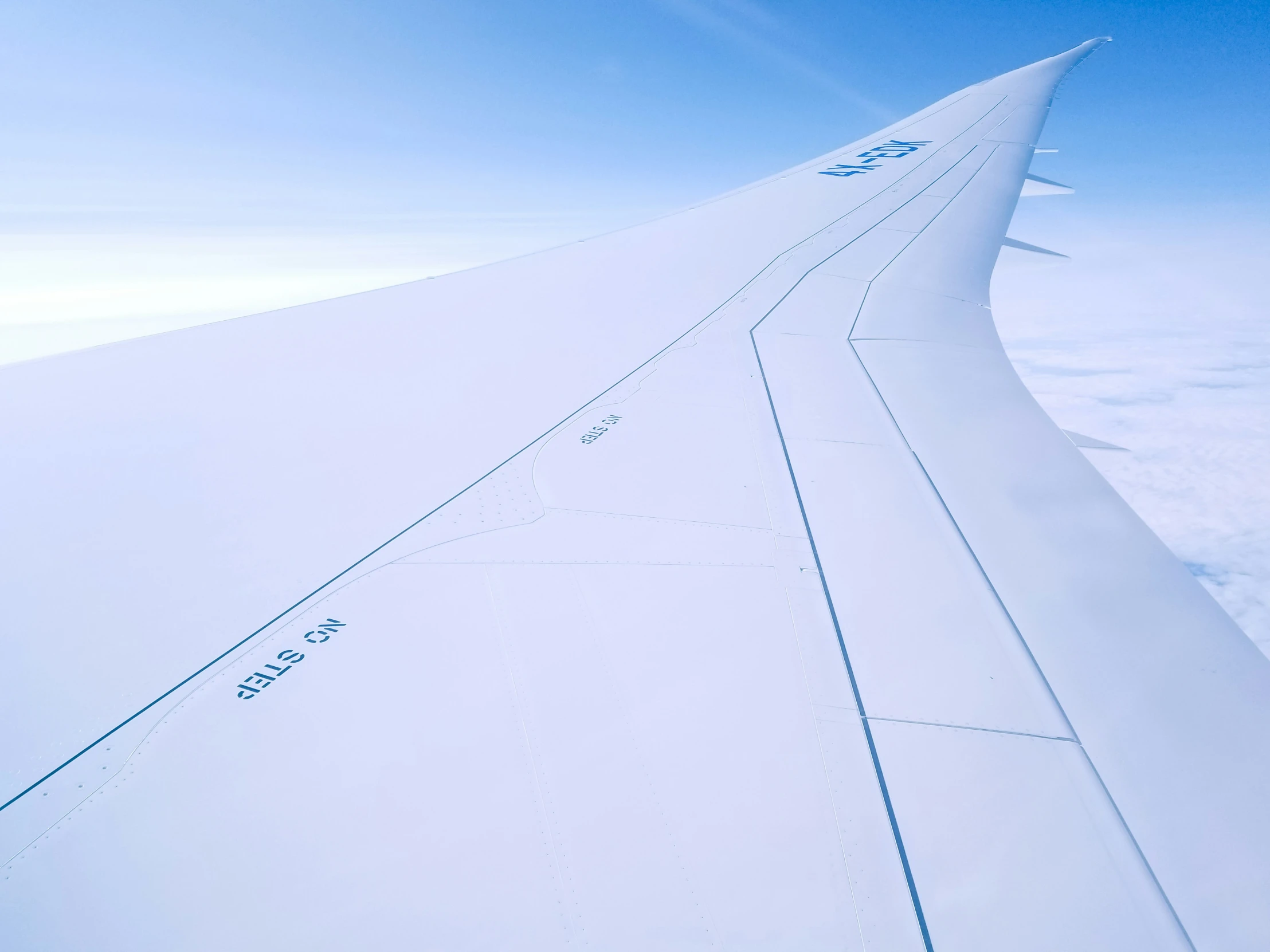 airplane wing flying in the air over clouds