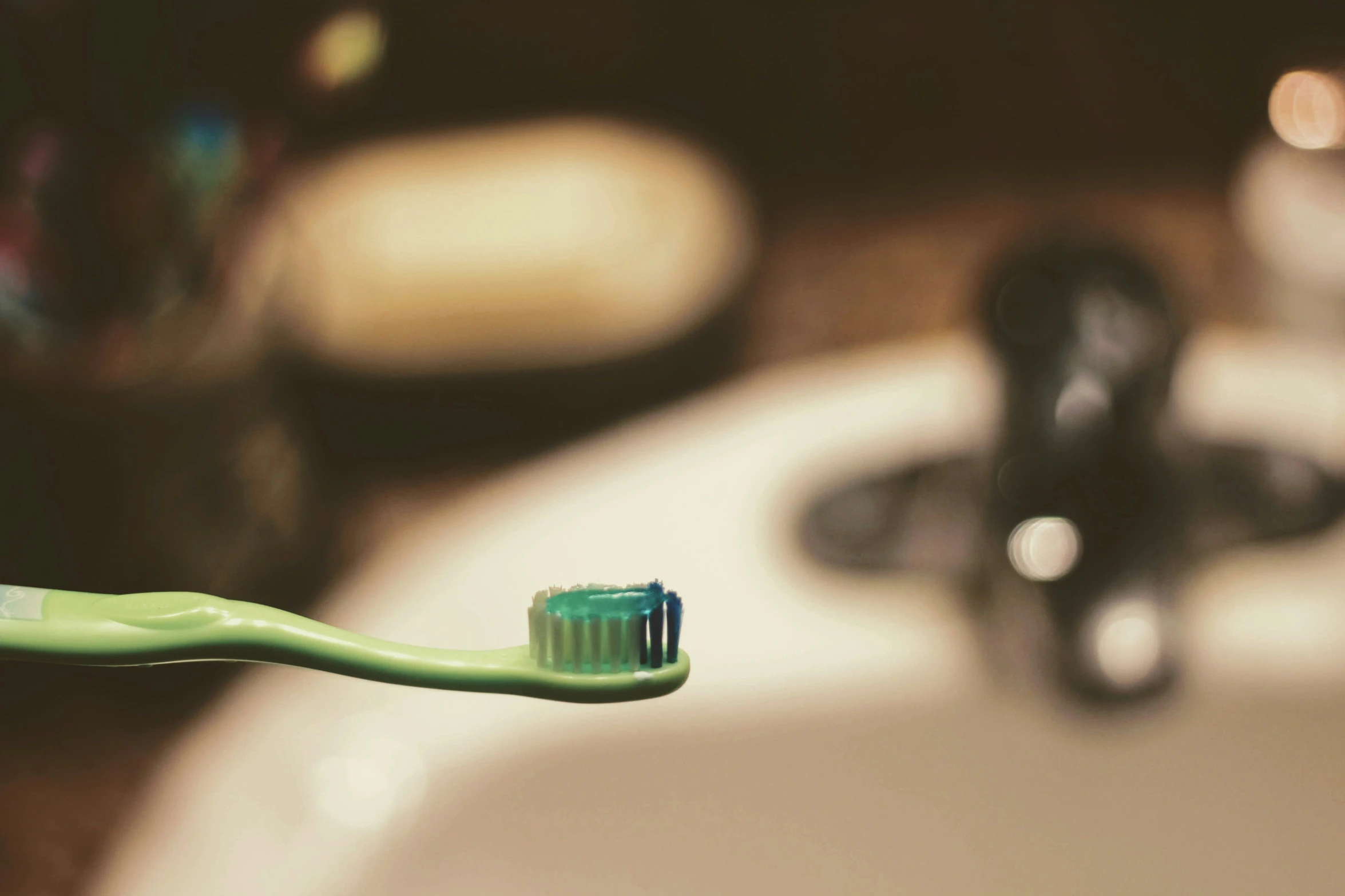 a green toothbrush with a long bristles in it's mouth