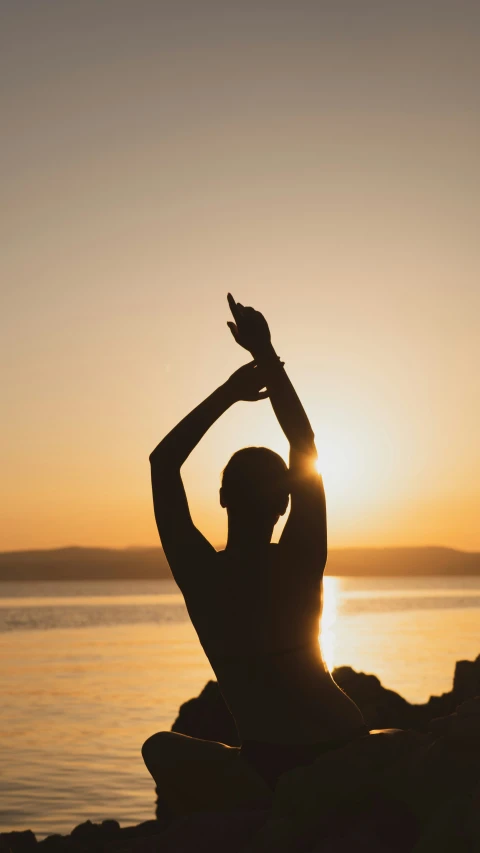 a person sitting on a beach with their arm raised