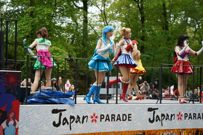 a line of girls wearing costumes that read japan parade, and some hold flags