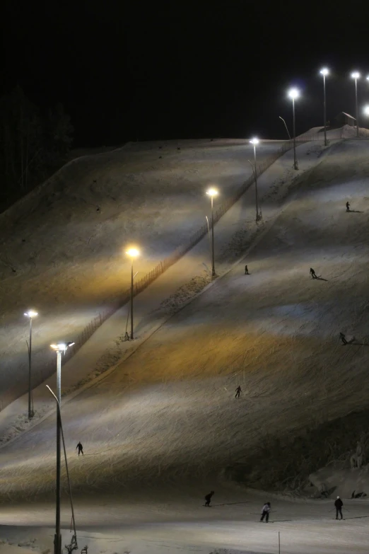 people are walking down a snowy slope at night