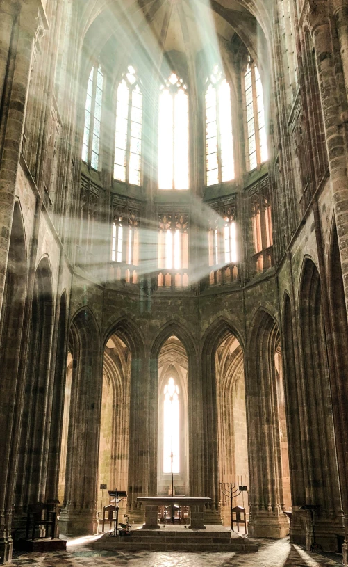 the sun shines through three windows in a large cathedral