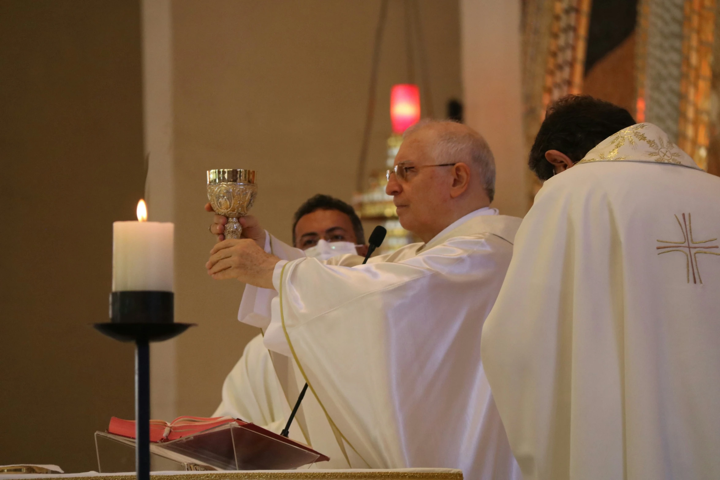 priest and nun pray together in front of a candle