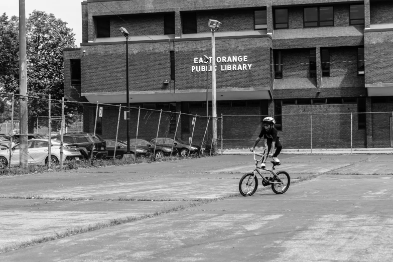 someone riding a bike past a building with parking lot