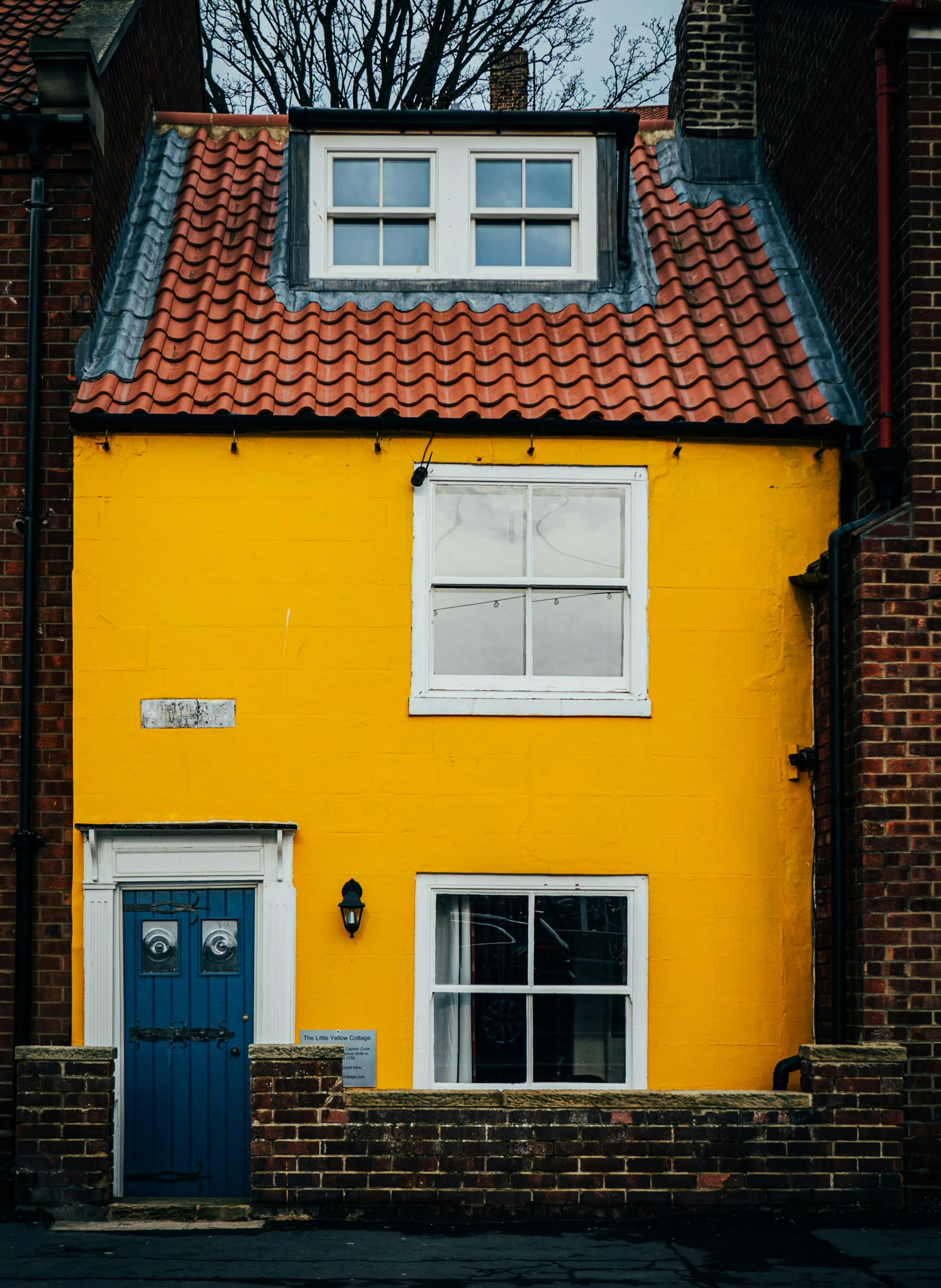 a yellow building with two windows and a green door