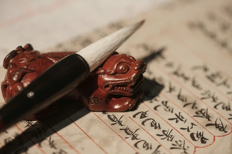 a pen and a small statue on some writing
