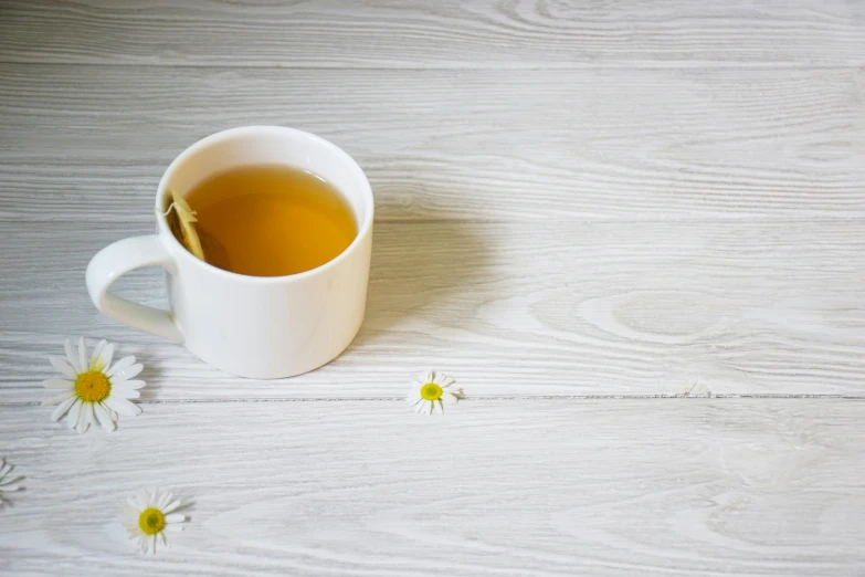 a cup of tea with daisy seeds around it