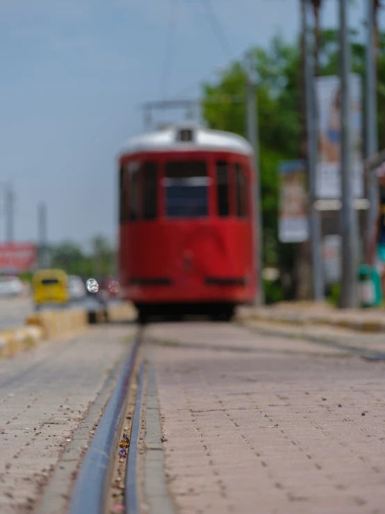 a red trolley traveling down the tracks on the street