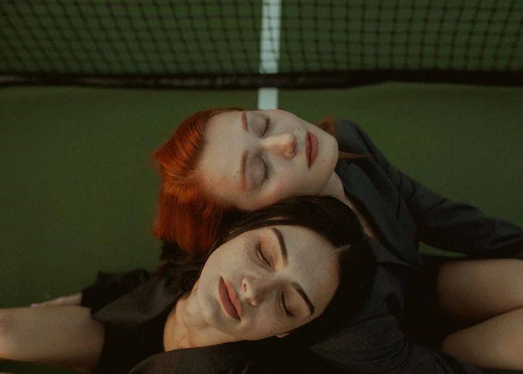 two people laying down together on a tennis court