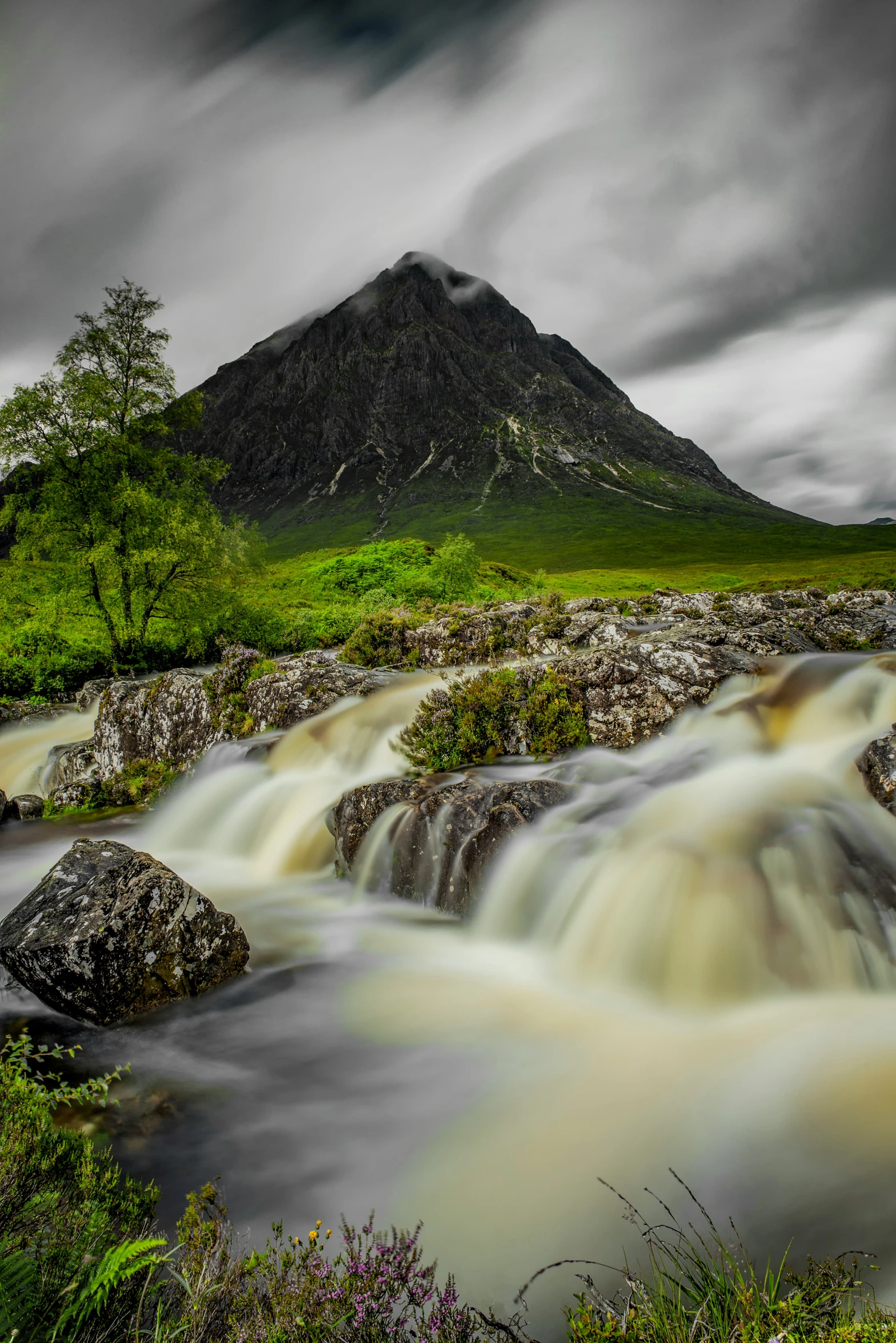 some water flowing next to a green hill