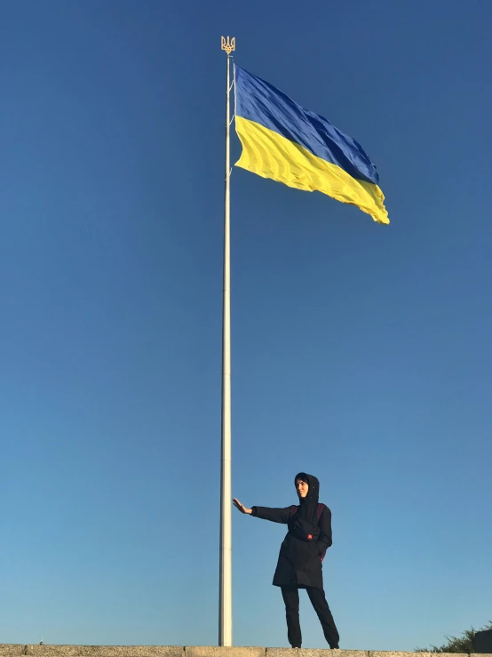 a man is standing under the flag on a tower