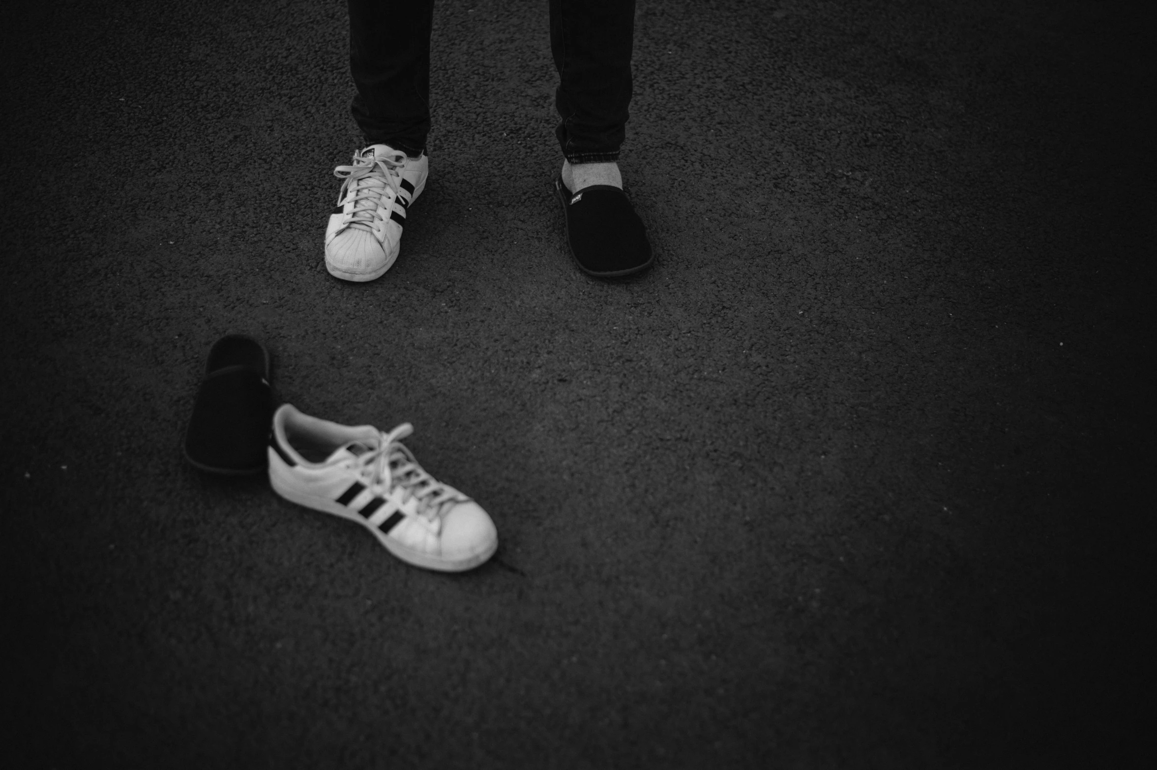 someone standing on the ground beside two shoes