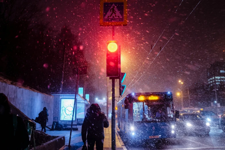 traffic lights are on as people board a bus in the snow