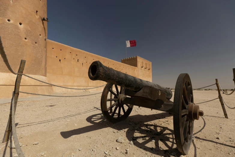 an old cannon in front of an adobe castle