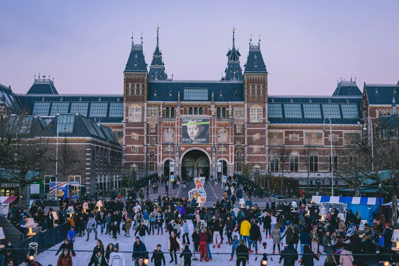 people walking around the courtyard on an evening with colorful lights