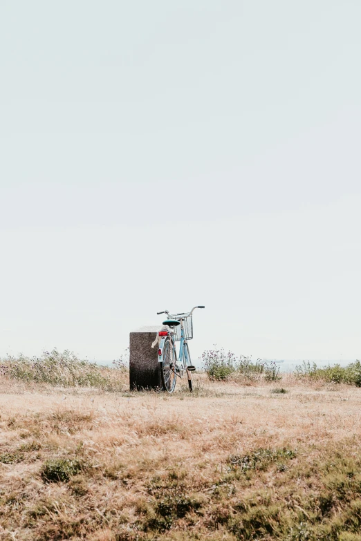 a bike in an empty grassy field next to a box