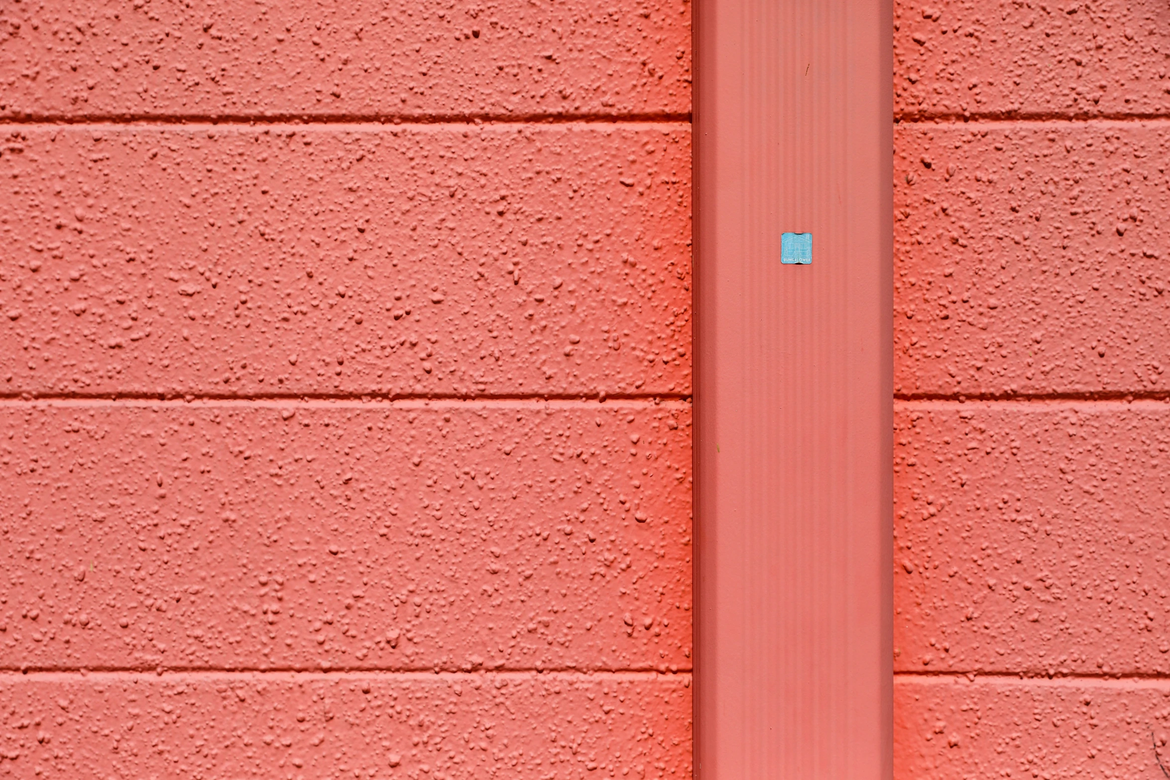 a white and black clock is on a pink wall