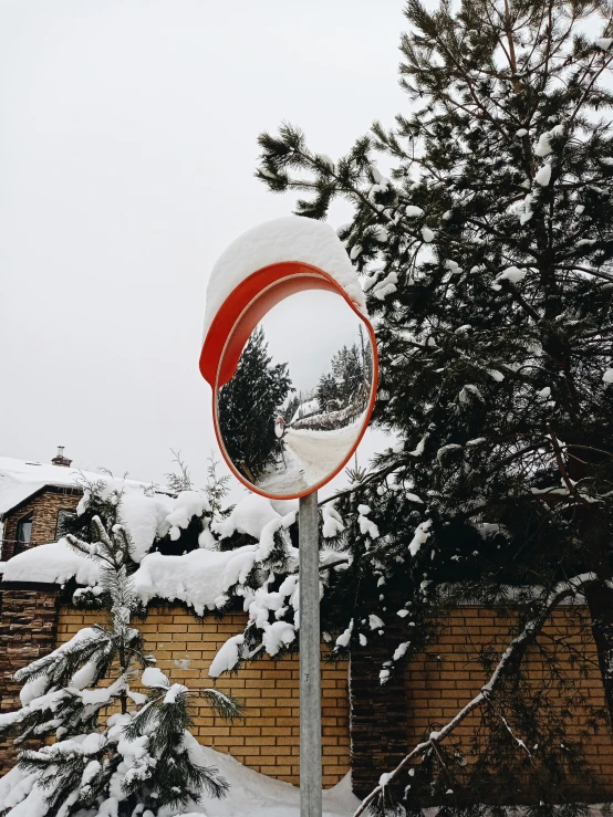 a snow covered street and a mirror by some trees