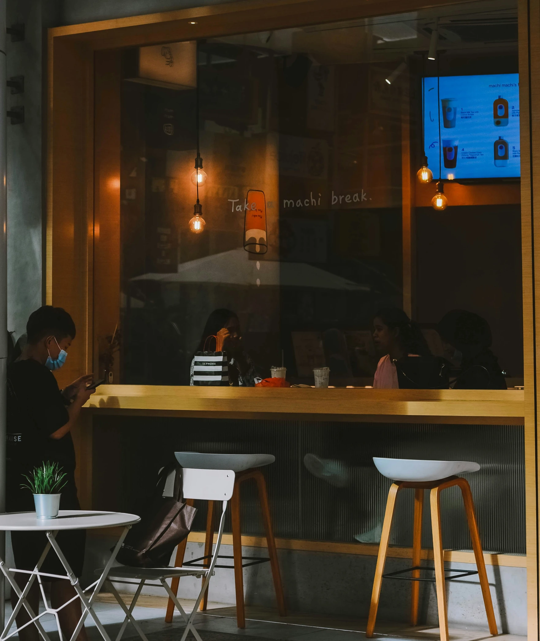 people sit at an outdoor restaurant with the television on