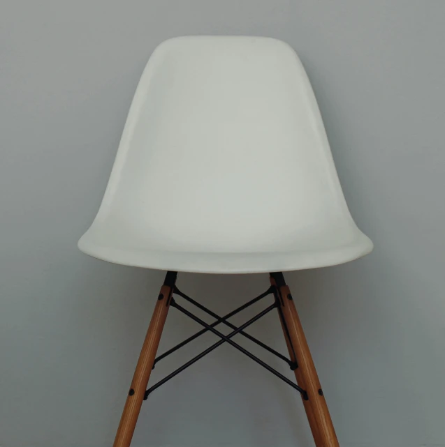 a white plastic and wooden chair against a gray wall