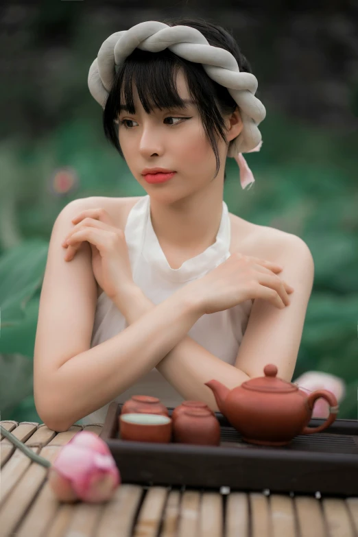 a woman that is sitting next to some tea kettles