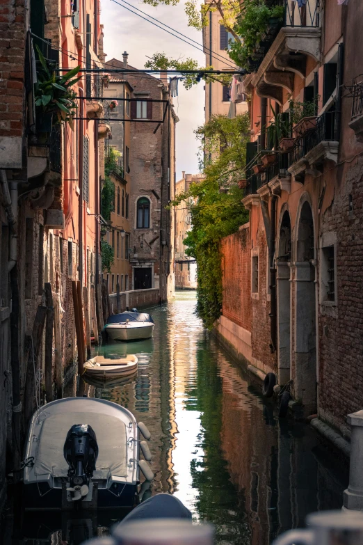 several boats floating down a narrow canal between buildings