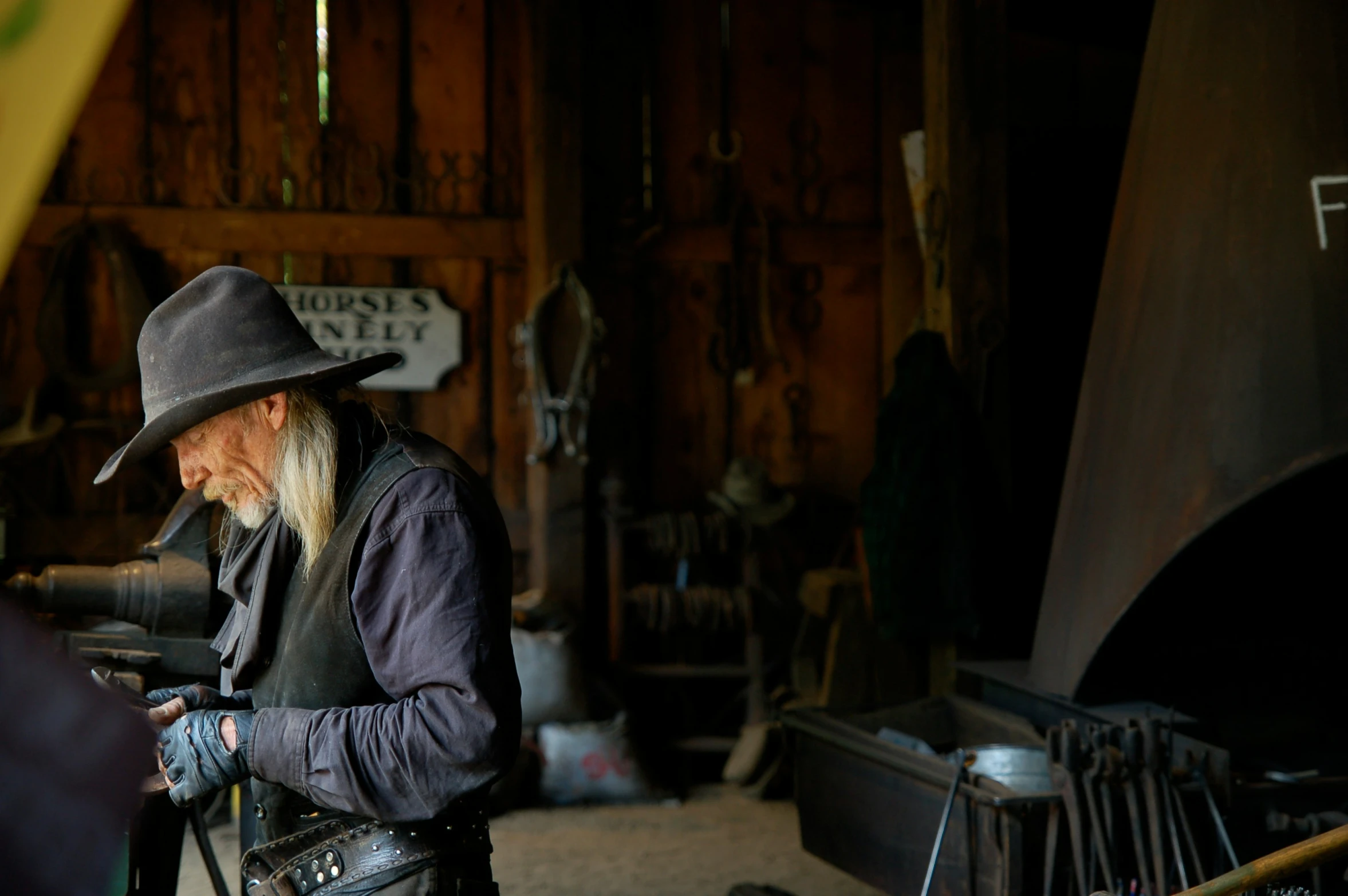 an elderly cowboy is wearing leather clothes and holding a bike