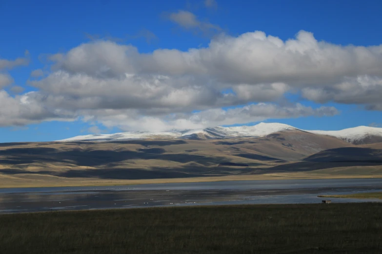 snow capped mountains rise above a lake near the plains