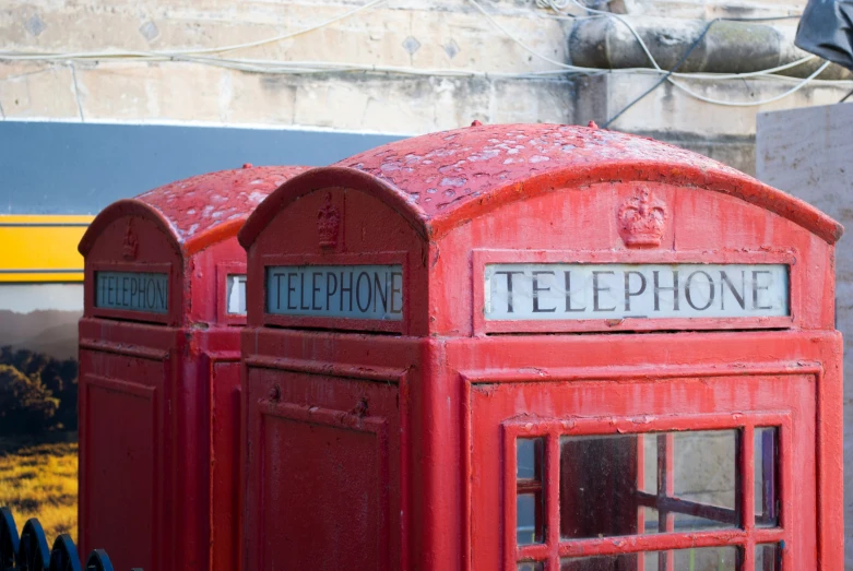 a line of red telephone booths sitting next to a train