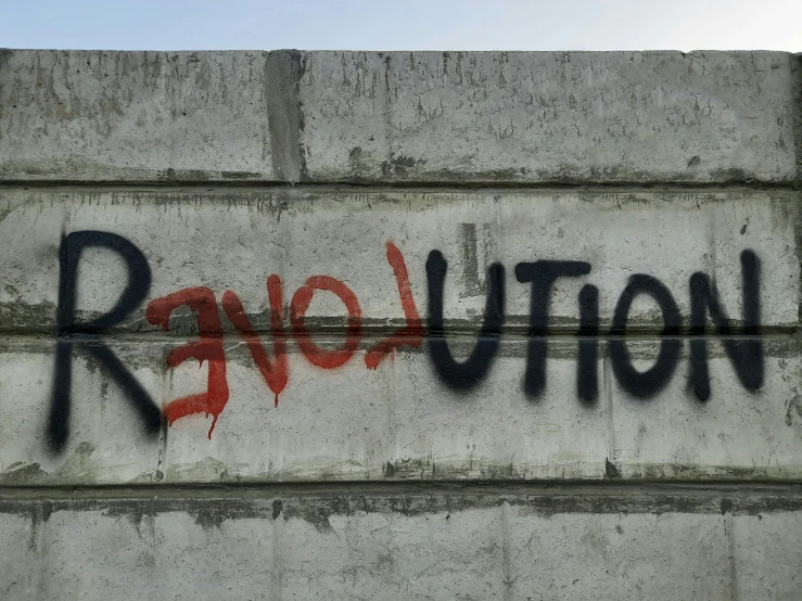 a wall has been sprayed with grafitti by a revolution sign