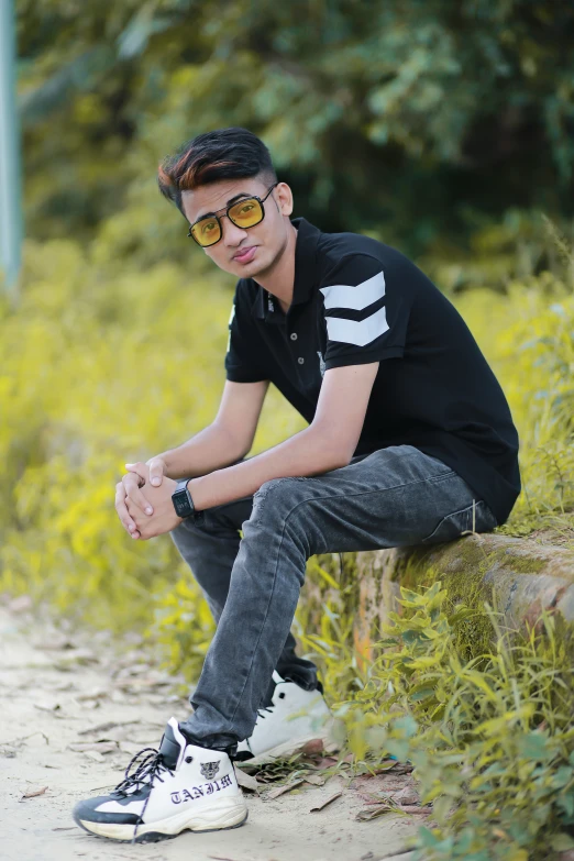 a young man wearing glasses while sitting on the side of a road